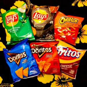 6 bags of chips, laid out horizontally in 2 rows of 3, in a background that is black with yellow flowers. The flavors are: Lays Sour Cream & Onion, Lays Barbecue, Cheetos Crunchy, Doritos Cool Ranch, Doritos Nacho Cheese, and Fritos Chili Cheese.